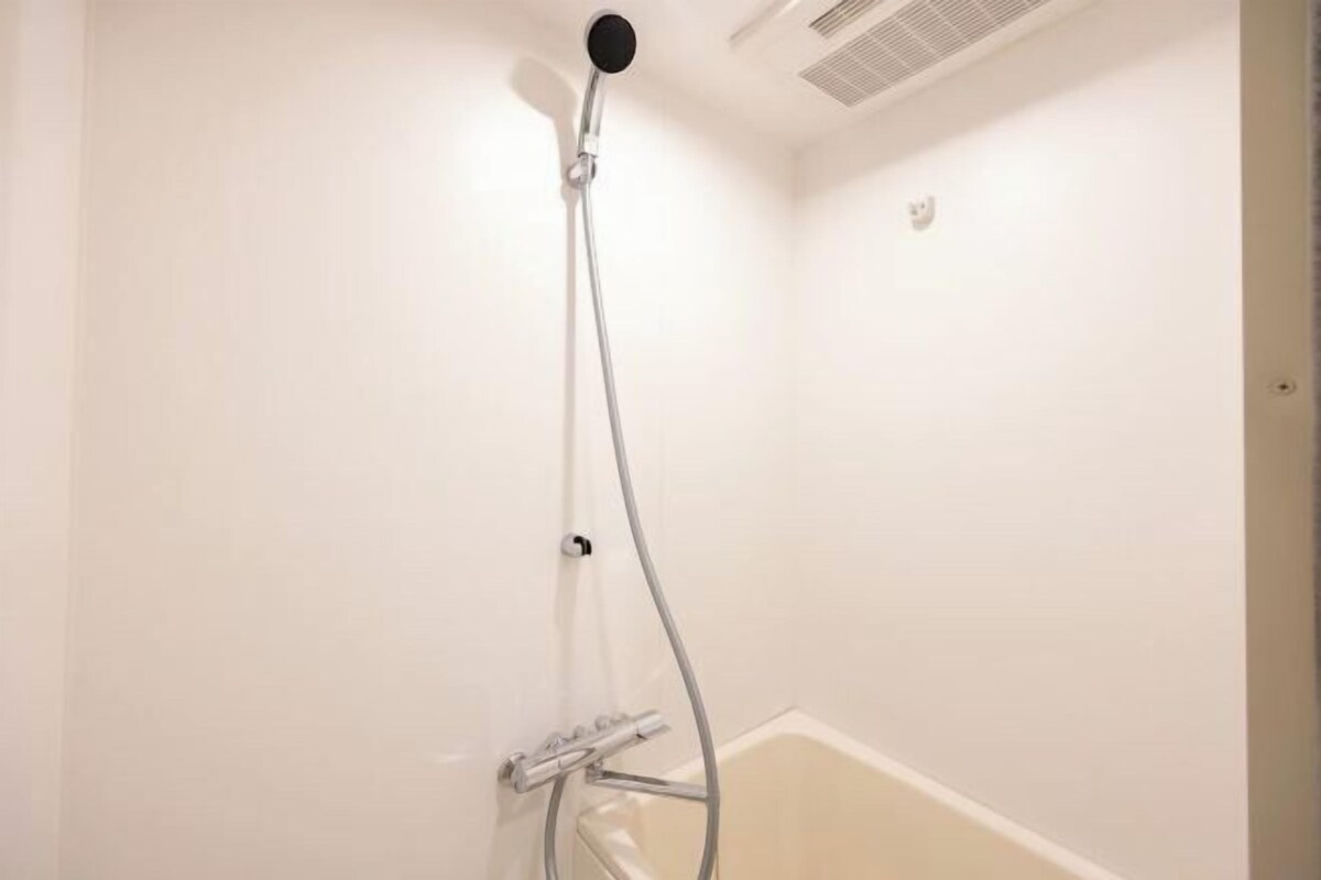 A shower with a handheld showerhead and a wall-mounted faucet.