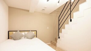 A bedroom with a bed, a headboard, a staircase, and a light fixture. - Retaw Hills Waseda (Tokyo)