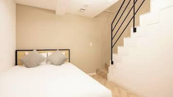 A bedroom with a bed, a headboard, a staircase, and a light fixture.