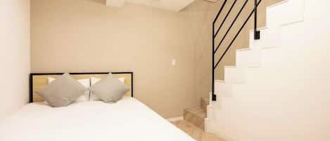 A bedroom with a bed, a headboard, a staircase, and a light fixture.