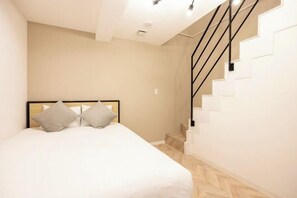 A bedroom with a bed, a headboard, a staircase, and a light fixture. - Retaw Hills Waseda (Tokyo)