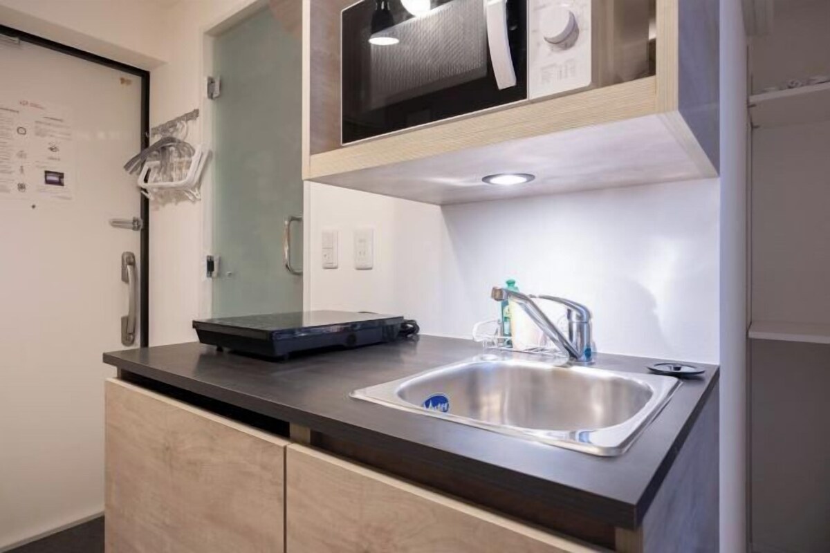 A compact kitchen with a stainless steel sink, a microwave, and a small countertop.