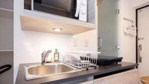 A kitchen with a stainless steel sink, a dish rack, and a microwave above the counter. - Retaw Hills Waseda (Tokyo)