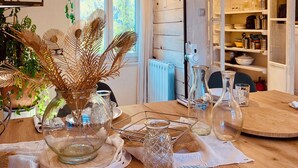 A dining area with a wooden table, clear glass vases, and a variety of kitchen utensils. - A P'tit Bali in the Cévennes, with Jacuzzi and breathtaking views! (le martinet)