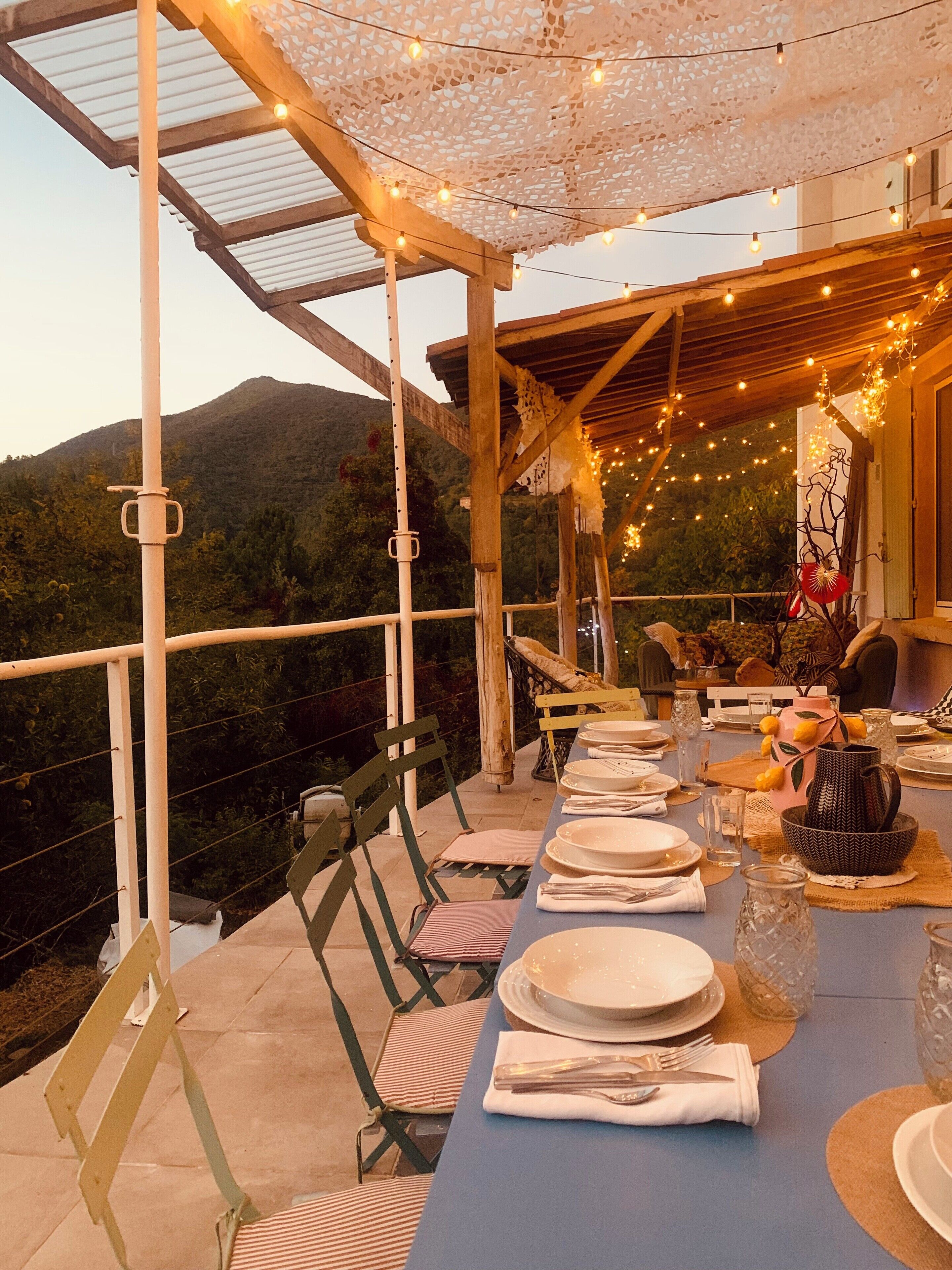 An outdoor dining area with tables set for a meal, overlooking a mountainous landscape.