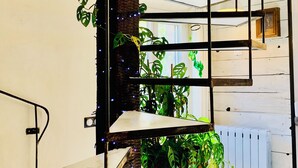 A spiral staircase with a potted plant at the bottom, surrounded by greenery and string lights. - A P'tit Bali in the Cévennes, with Jacuzzi and breathtaking views! (le martinet)
