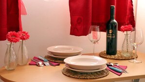 Una tavola imbandita con piatti, posate e una bottiglia di vino, con tende rosse sullo sfondo.