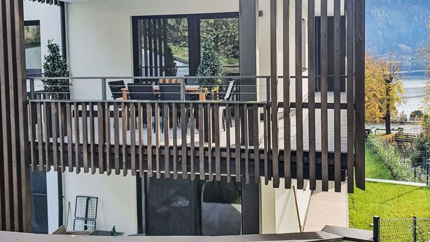 A modern building with a balcony, large windows, and a view of a lake. - Beautiful apartment for 5 people with WIFI, TV and balcony (Sattendorf)