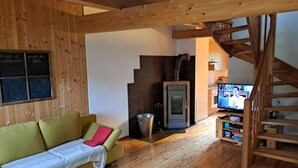 Uma sala de estar acolhedora com piso de madeira, um sofá, uma lareira e uma televisão.