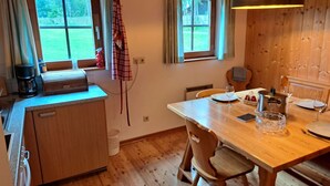 Uma cozinha acolhedora com armários de madeira, uma mesa de jantar com cadeiras e uma janela com vista para um jardim.