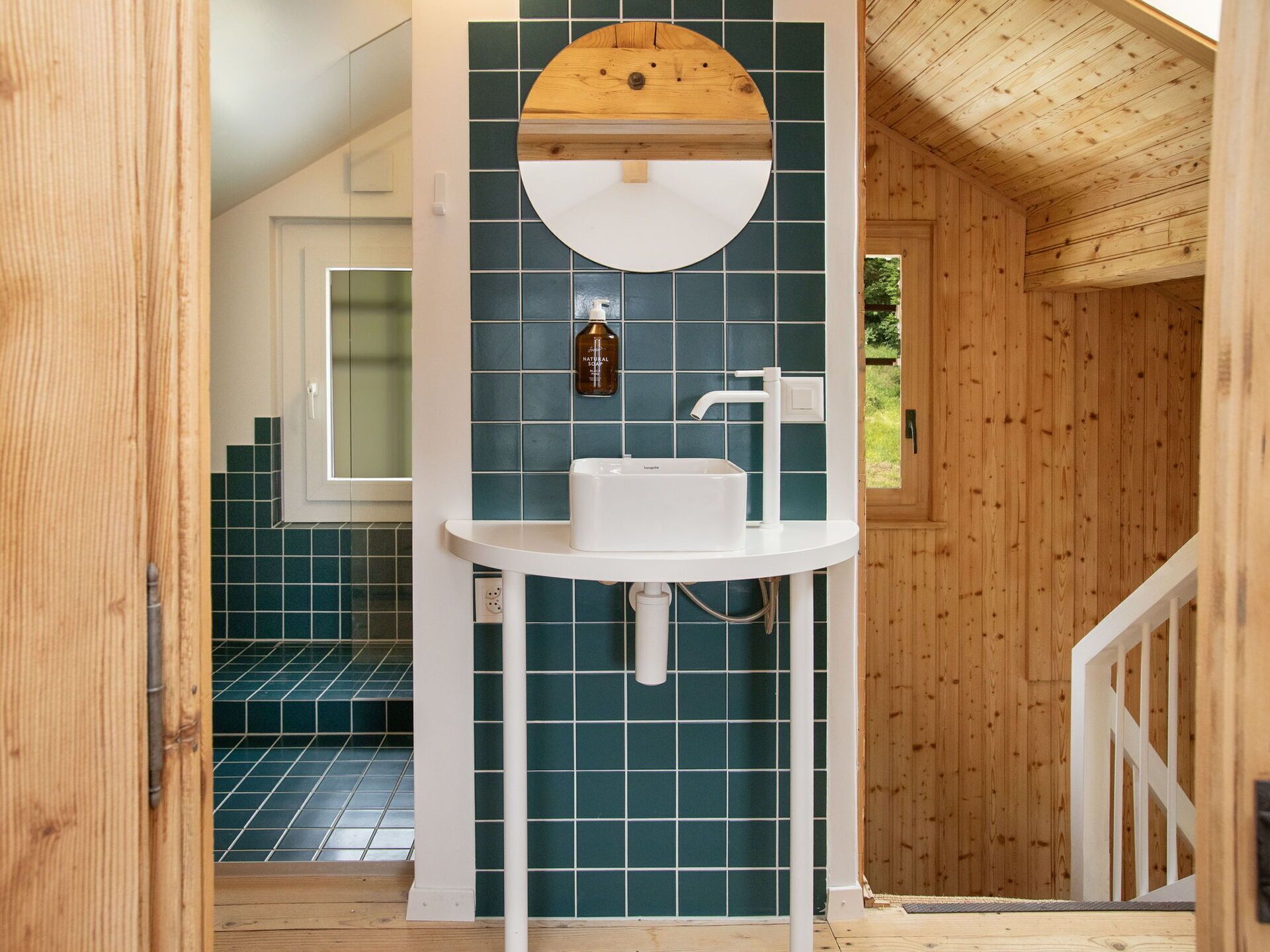 Ein Badezimmer mit einem weißen Waschbecken, einem Spiegel und einer Seifelflasche an der Wand.