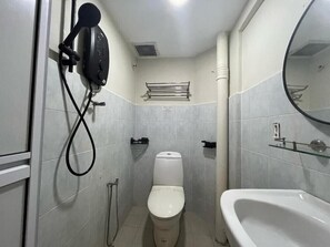 A bathroom with a toilet, a shower with a handheld showerhead, a sink, and a mirror. - Swing and Pillows @ Malacca Mahkota Parade (Melaka)