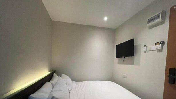 Una habitación de hotel con una cama, un televisor de pantalla plana montado en la pared y un equipo de aire acondicionado de pared.
