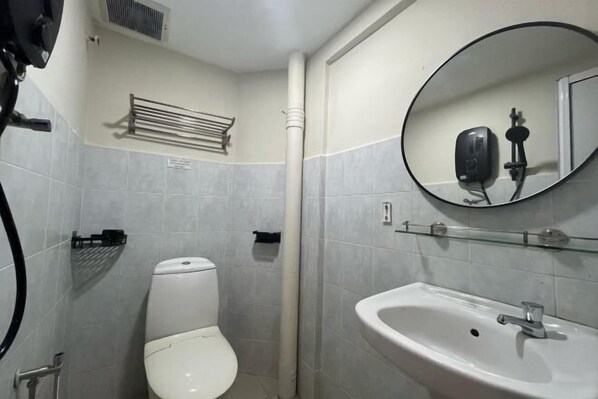 Ein kleines Badezimmer mit Toilette, Waschbecken, Spiegel und einem Handtrockner.