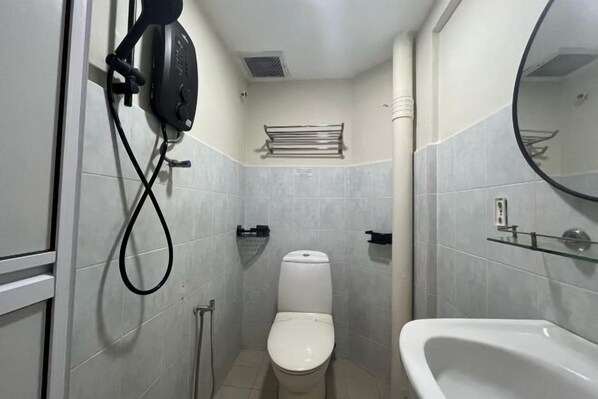 A compact bathroom with a toilet, a glass shower enclosure, and a white bathtub. - Swing and Pillows @ Malacca Mahkota Parade (Melaka)