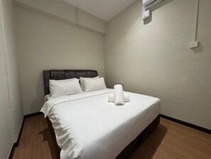 A hotel room with a single bed, white linens, a dark headboard, and a wall-mounted air conditioning unit. - Swing and Pillows @ Malacca Mahkota Parade (Melaka)