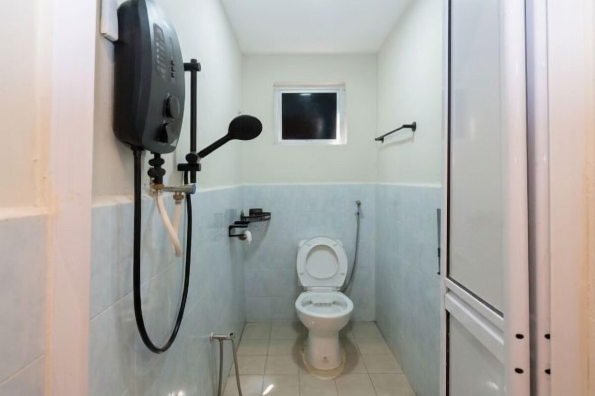 A small bathroom with a toilet, a hand dryer, and a shower hose.
