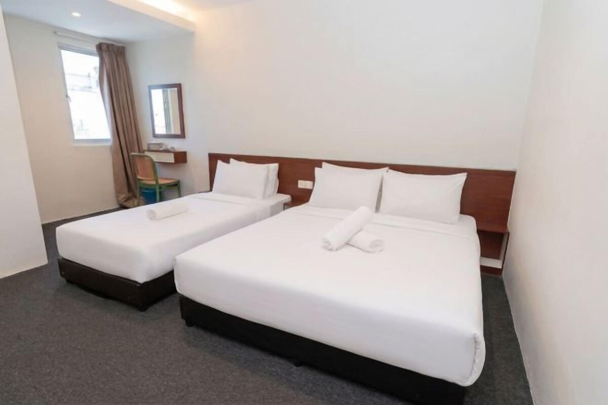 A hotel room with two beds, a window, and a mirror.