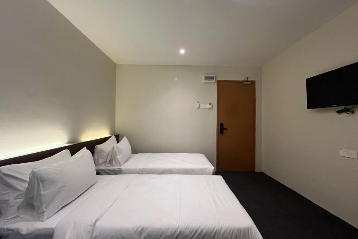Une chambre d’hôtel avec deux lits, un téléviseur fixé au mur et une porte.