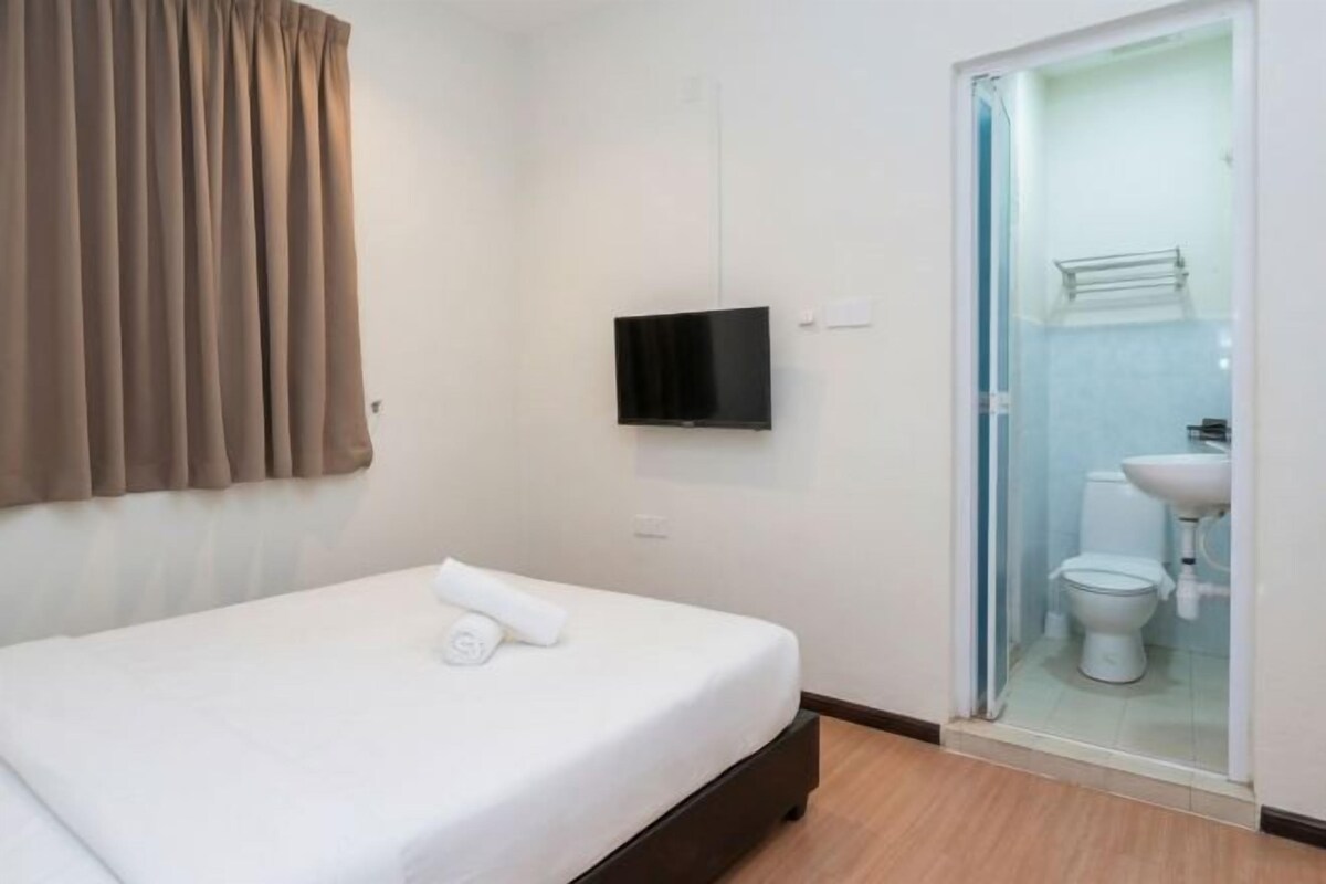 Habitación de hotel con cama, televisión, baño con inodoro y lavamanos, y zona de ducha.