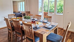 Un coin repas avec une table en bois dressée pour quatre personnes, entourée de chaises en bois dotées d’assises rembourrées.