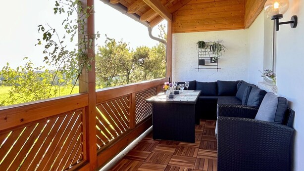 Un espace extérieur abrité, doté d’un plafond en bois, d’une table avec des verres et d’un canapé.