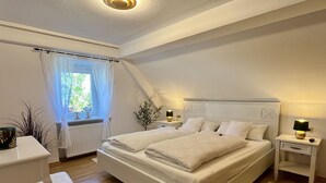 Une chambre Ă coucher avec un grand lit, deux tables de chevet, un bureau et une chaise.