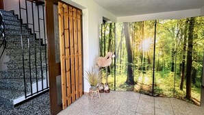 Un escalier avec une rampe en bois, un mur orné d’un lambris vertical en bois et une grande fresque représentant une forêt sur le mur.