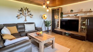 Un salon moderne avec un canapé en cuir, une table basse en bois et un grand téléviseur à écran plat.