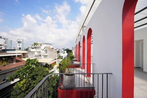 Een balkon met uitzicht op omliggende gebouwen en een heldere lucht.