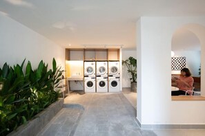 A laundry room with a washing machine and dryer, a sink, and a potted plant. - Express by M Village 59 Thao Dien, a brand of Modern Village Lifestyle (Ho Chi Minh City)