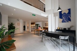 A modern hotel lobby with a dining area, a staircase, and a large abstract painting. - Express by M Village 59 Thao Dien, a brand of Modern Village Lifestyle (Ho Chi Minh City)
