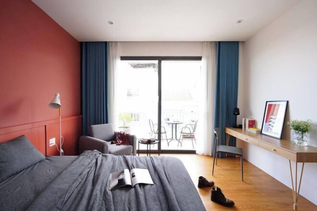 A modern hotel room with a large bed, a desk, and a balcony with a view.