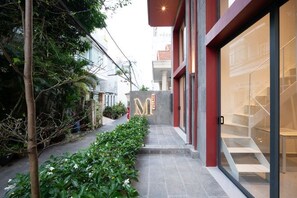 A modern building with a glass facade, a visible staircase, and a pathway lined with greenery. - Express by M Village 59 Thao Dien, a brand of Modern Village Lifestyle (Ho Chi Minh City)