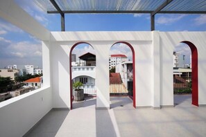 A rooftop terrace with a clear view of the cityscape, featuring a covered area with red arches and a white wall. - Express by M Village 59 Thao Dien, a brand of Modern Village Lifestyle (Ho Chi Minh City)