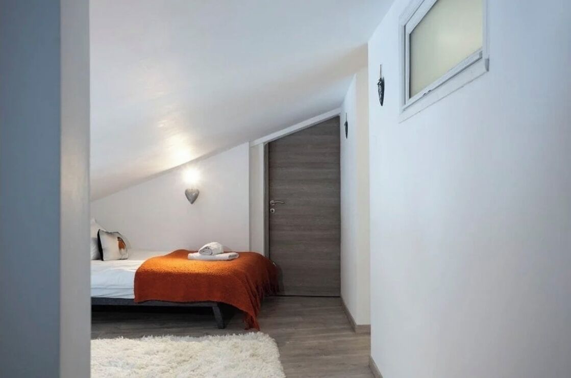 Ein kleines, gemütliches Schlafzimmer mit einem Einzelbett, einem weißen Teppich und einer Holztür.