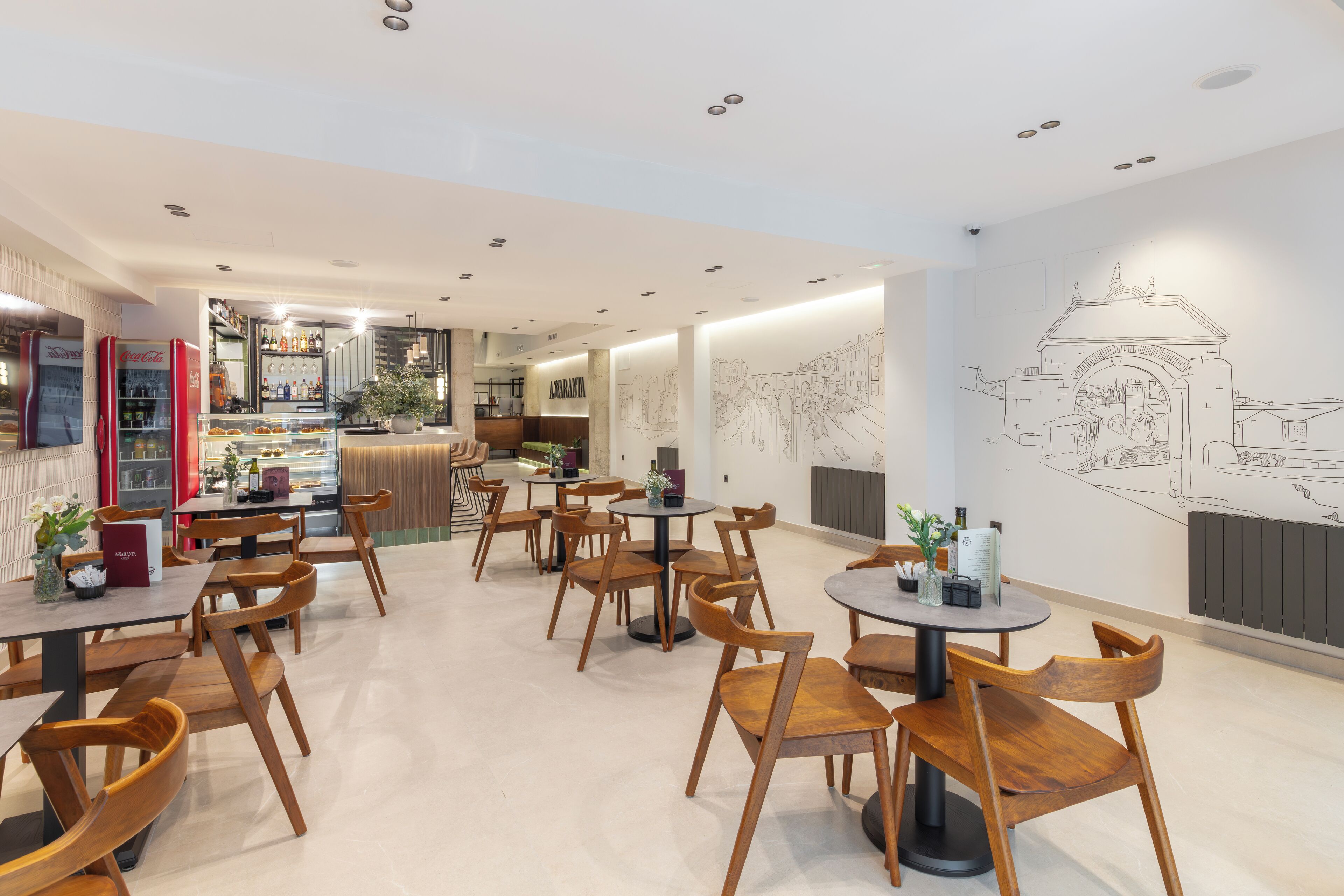 Ein modernes Café mit Holztischen und -stühlen, einer Bar und einer Wand mit einer Stadtansicht als Zeichnung.