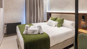 Una cama bien hecha con un edredón verde, sábanas blancas y dos almohadas verdes.