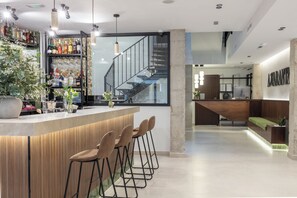 Zona de bar moderna amb un taulell de fusta, tamborets i una escala que condueix a un nivell superior.