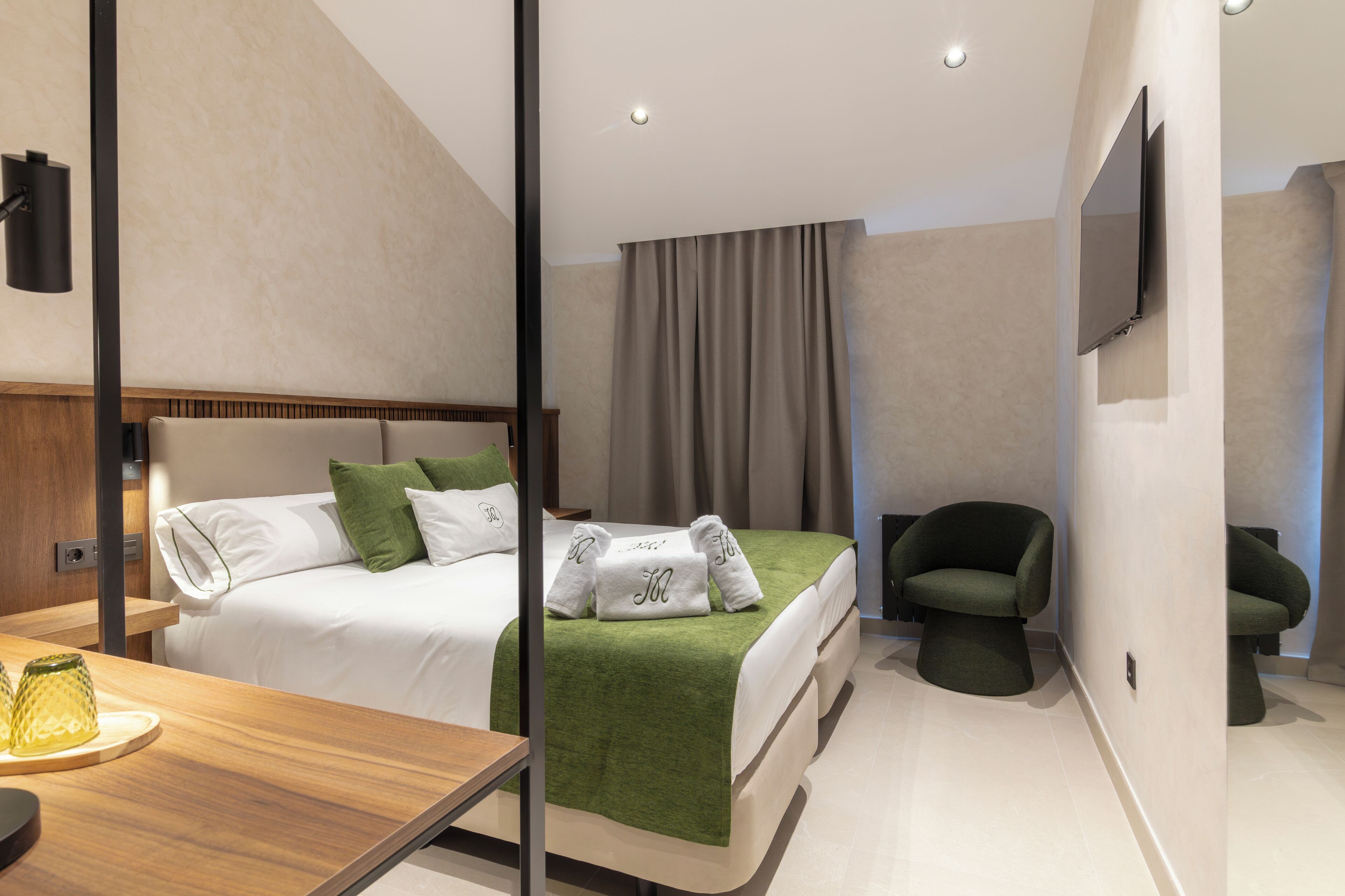 Ein modernes Hotelzimmer mit einem Bett, einem Schreibtisch, einem Sessel und einem Fernseher.