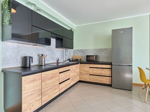 Een moderne keuken met donkere kastjes, een roestvrijstalen koelkast en een houten aanrecht.