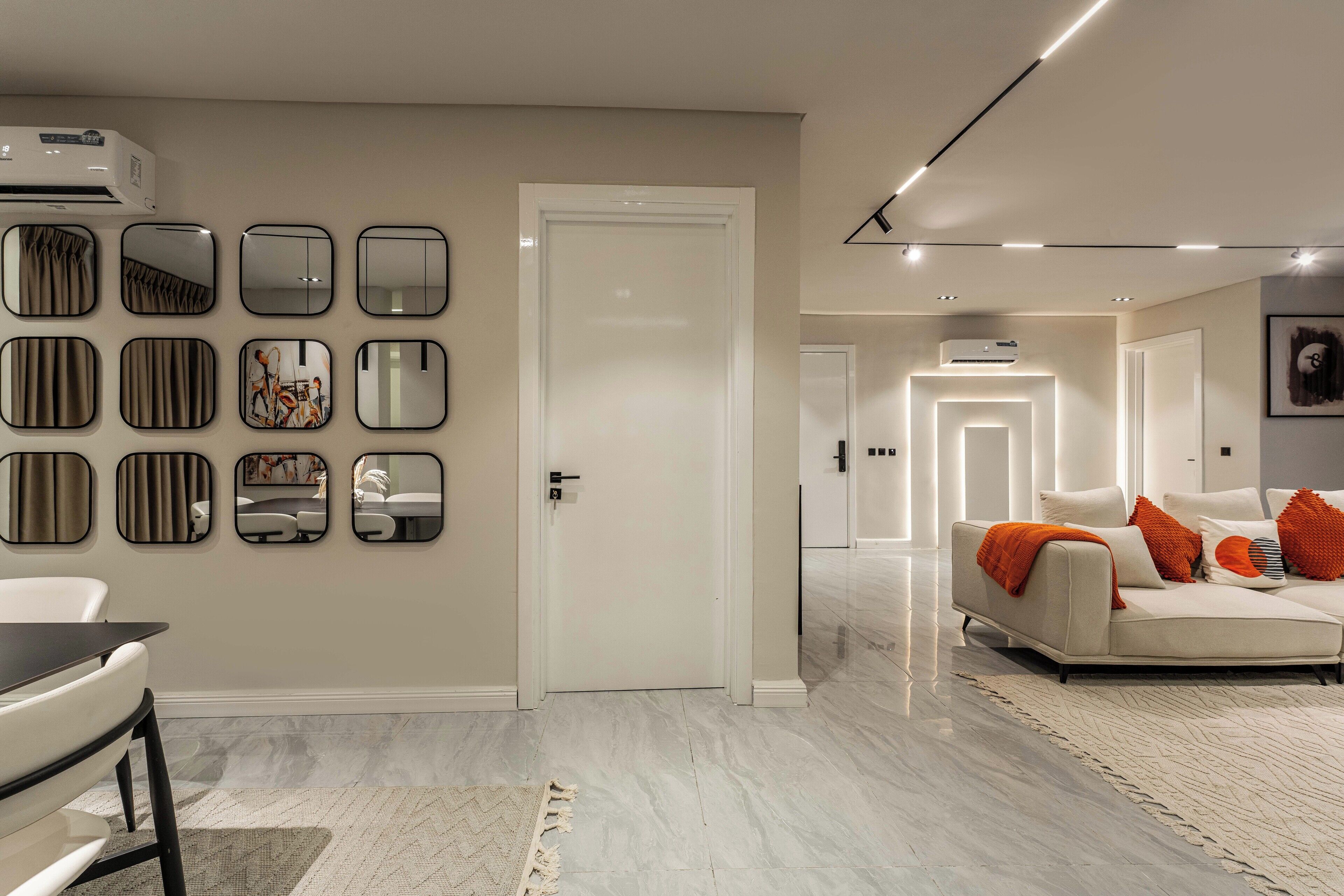 A modern living room with a sofa, a dining table, and a white door.