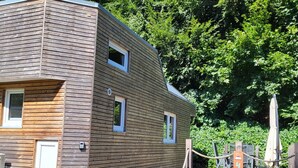 Eine Holzhütte mit einer kleinen Veranda und einem Seilzaun.