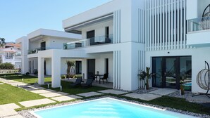 A modern multi-story residential building with a swimming pool, outdoor seating, and a clear sky. - White Dream One-bedroom Apartment With Pool Access (Thasos)