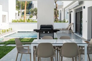 An outdoor patio with a barbecue grill, a pool, and a dining area with chairs and a table. - Emerald Three-Bedroom Villa with Private Pool and Rooftop (Kavala)