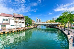 Un canal bordé de bâtiments des deux côtés, un ciel dégagé et une vue lointaine sur des immeubles modernes.
