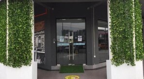 A hotel entrance with a glass door, a green mat, and a wall with greenery. - 96 Boutique Hotel (Melaka)