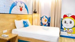 A hotel room with a bed, bedside table, and a wall with cartoon character decorations. - 96 Boutique Hotel (Melaka)