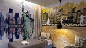 Une chambre avec une fresque représentant la Statue de la Liberté, un paysage urbain et un lit avec un oreiller.
