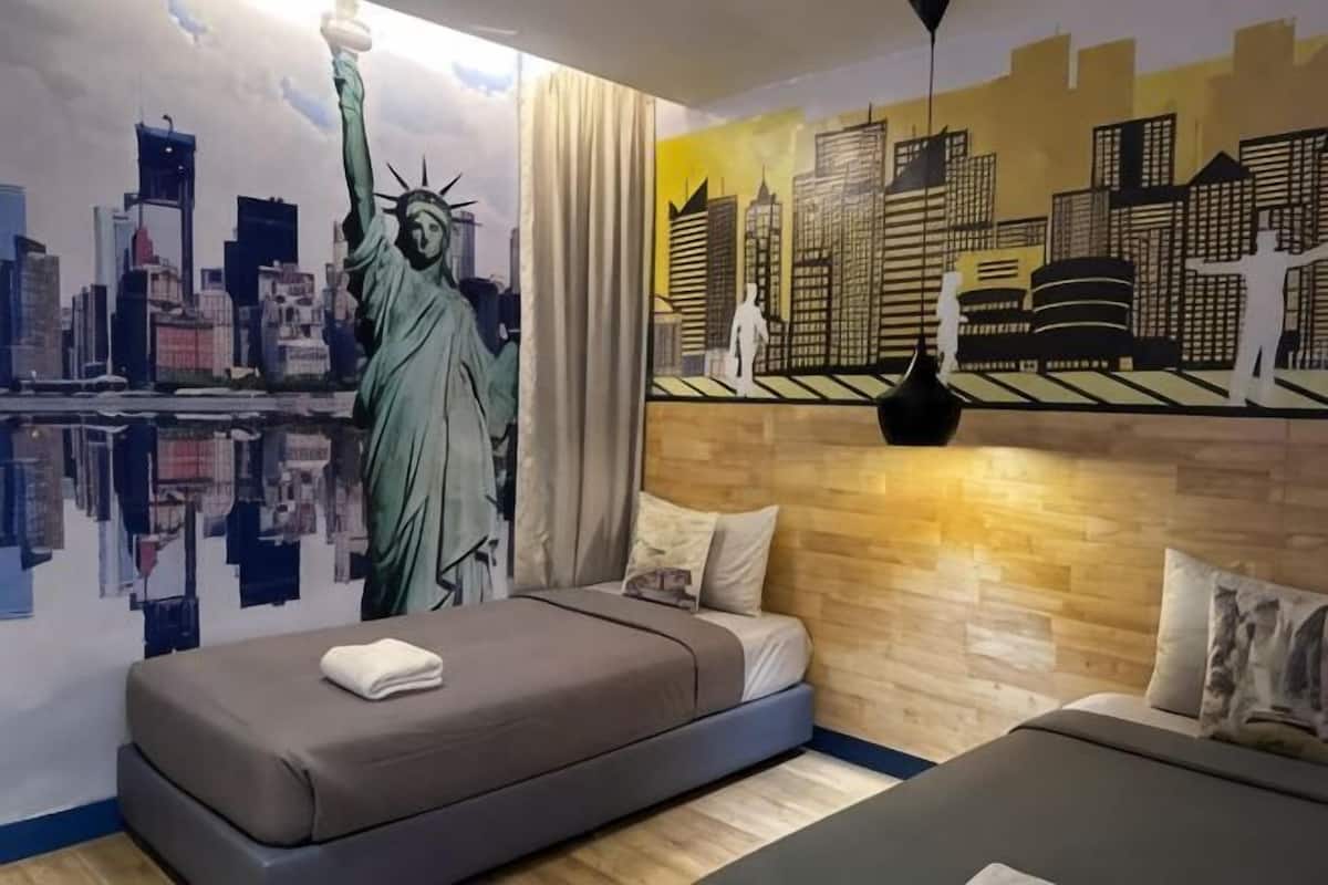 Un dormitorio con un mural de la Estatua de la Libertad, un paisaje urbano y una cama con un almohadón.